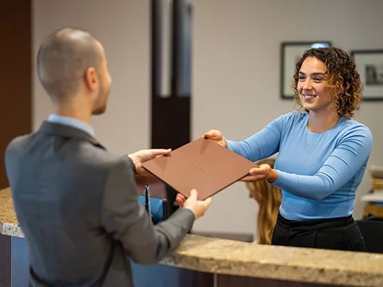 A Servcorp team member hands a secure envelope to a client at reception at Boulevard Plaza, Dubai