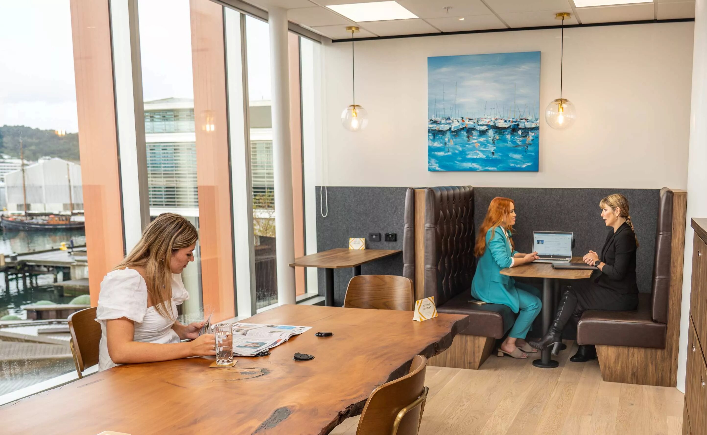 Clients working in a modern coworking shared space on a long table with great booths in Servcorp Bell Gully Building, Wellington